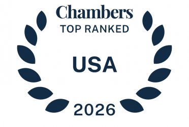 Dark blue icon in the shape of a laurel wreath that says Chambers Ranked In USA 2026 Phil Blumstein.
