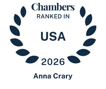 Dark blue icon in the shape of a laurel wreath that says Chambers Ranked In USA 2026 Anna Crary.
